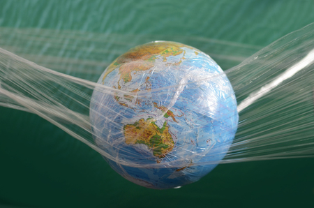 The earth is suspended in a plastic plastic disposable packaging. The concept of environmental pollution by polyethylene plastic waste, environmental problems. Stop plastic pollution. In the form for social advertising there is a place for an inscription.の写真素材