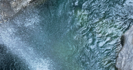 Mountain waterfall from glacial peaks melts in turquoise river. Top view, clean water stream flows...
