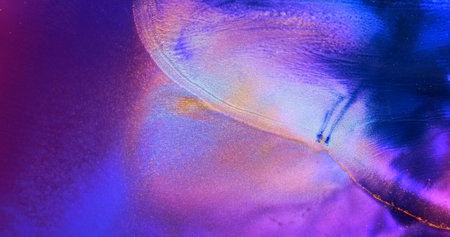 Blue dye spreads on lilac paint background. Blue colorful wave flow on shiny bright purple-pink ink...