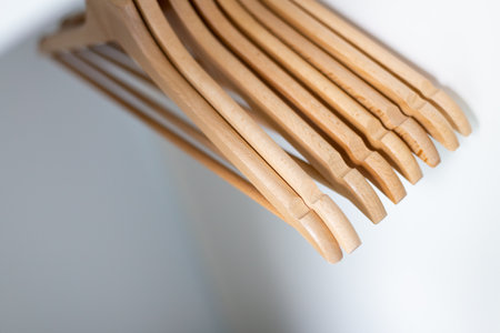 close up of cloth wooden hangers in row on white background. Hangers in wardrobeの写真素材