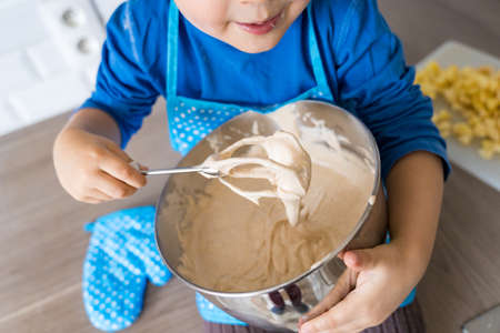 Adorable little boy helping and baking apple pie in home''s kitchen, indoor. Child wearing apron and toque kneading and mixing doughの写真素材