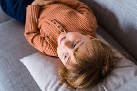 Young boy is lying on the couch and looking aside. Toddler falling sick and relaxing on the sofa....
