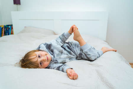 Little toddler boy relaxing on bed. Home leisure. Child playing in bed.の写真素材