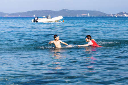 Two boys are playing in a water. Children havinbg fun in the sea. Brothers spend time together at the seaside during holidays.の写真素材
