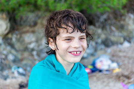Boy of ten years old wrapped in towel after swimming in the sea. Summer beach vacation concept. Holidays in France.の写真素材