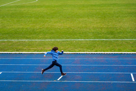 Scool boy running outdoors. Child doing athletics at the stadium. Sport concept for kids.の写真素材