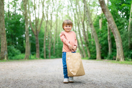 Little boy carrying a paper bag after a successful shopping ia moll. Shopping with children during sales. Black friday concept.の写真素材