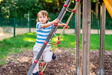 Sweet little boy playing in a park on playground. Toddler looking away climbing a slide. Summer...
