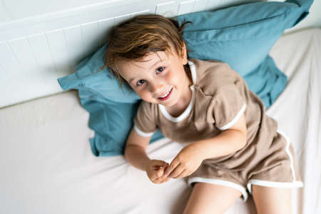 Close up portrait of a child lying in a bed in the morning. Adorable toddler wearing pajamas waking...
