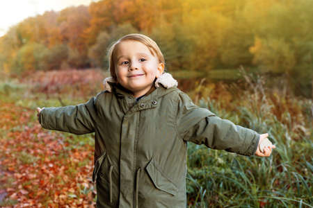 Happy little boy walking in a beautiful autumn park. Playful toddler spending fall weekend in a...