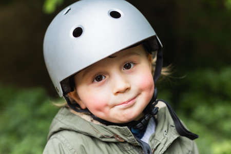 Close up portrait of a cute three year old boy wearing a safety helmet for riding a bicycle.の写真素材