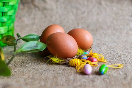 Easter eggs and small decorative eggs on brown sackclothの写真素材