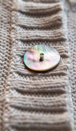 Detail of knitted white cotton with mother of pearl button. Knitting fabric cotton.の写真素材