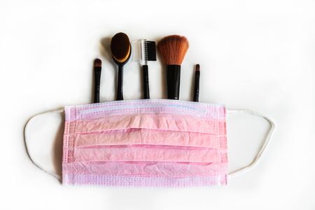 Professional makeup brush set covered by pink mask on white background. Brush set isolated on white...