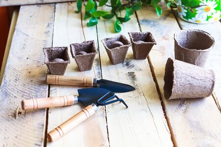 Biodegradeble pots, rake and spade on wooden background. Garden tools.の写真素材