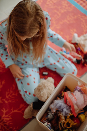 Selective focus on little girls hair sitting on carpet and playing with toys in a plastic box, top view, concept of child playing with toys. High quality photoの写真素材