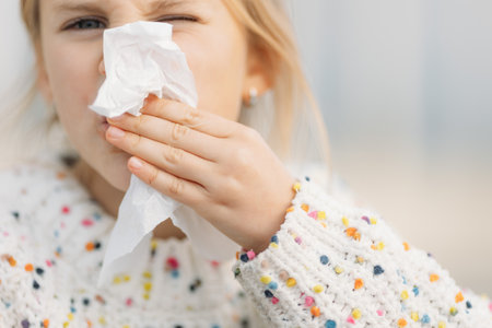 Close up up little girls hand in white dotted sweater wiping her face with napkin outdoors. High quality photoの写真素材