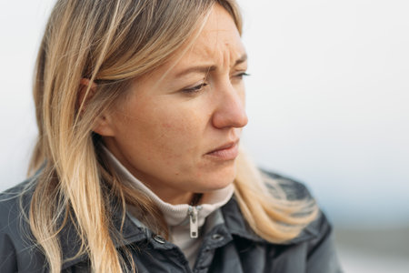 Close up of woman face with frowning expression and wrinkles, woman is troubled and upset, woman bent brows. High quality photoの写真素材