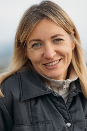 Portrait of a smiling beautiful woman looking at camera, happy woman outdoors wearing jacket. High quality photoの写真素材