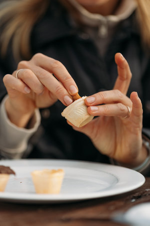 Woman hands in black jacket holding crepe in cafe outdoors choosing topping in waffle cups. High quality photoの写真素材
