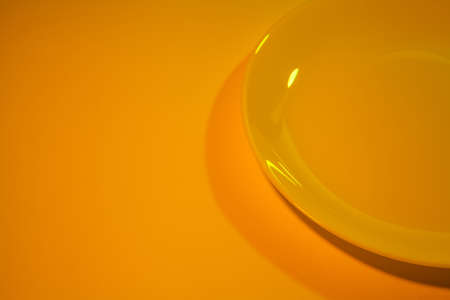 Abstract picture of simple ceramic white dish lit with bright orange-yellow light.の写真素材