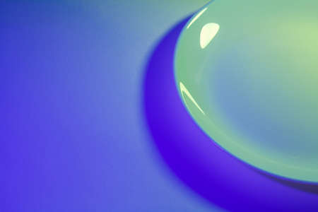 Abstract picture of simple ceramic white dish lit by two lights in ultraviolet and lime green.の写真素材