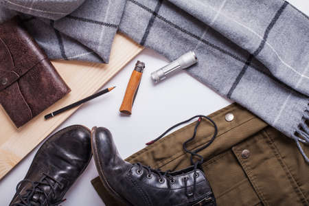 Wanderlust flatlay composition consisting of khaki jacket, grey scarf, leather notepad, pencil, knife and led light.の写真素材