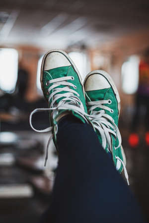Authentic picture of streched out and crossed female legs wearing with old green sneakers with...