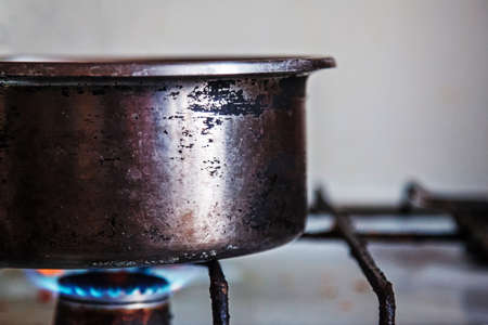 Old scratched metal cooker placed on a burning gas stoveの写真素材