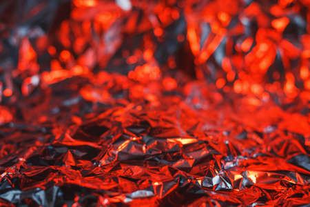 Modern abstract foil background lit by colorful red and orange lamp resembling fireの写真素材