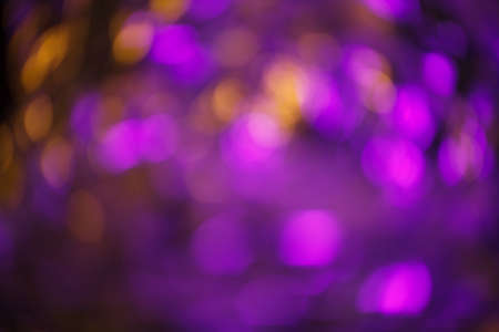 Modern abstract bokeh blurred foil background lit by pink and yellow lamp creating festive party moodの写真素材