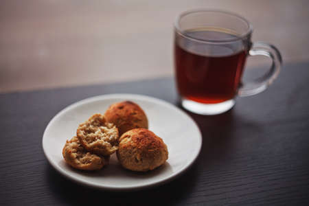 Midday snack consisting of three little curd and oatmeal buns with a cup of black tea, one bun...