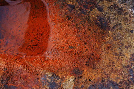 Bright picture of a pool of water filling a natural rust covered cavern in piece of concrete