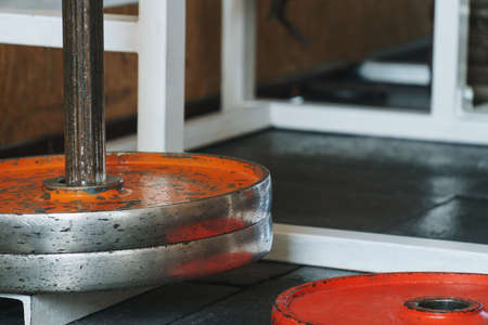 Abstract hardcore gym theme background with bright orange painted chapped old weight plates placed...