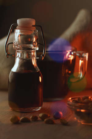 Small bottle of syrup, cup of black coffee and small transparent glass cup filled with peanuts -...