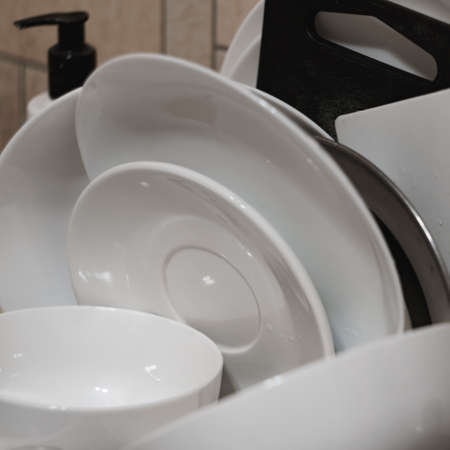 Bunch of just washed dishes piled upon a drier in a squareの写真素材