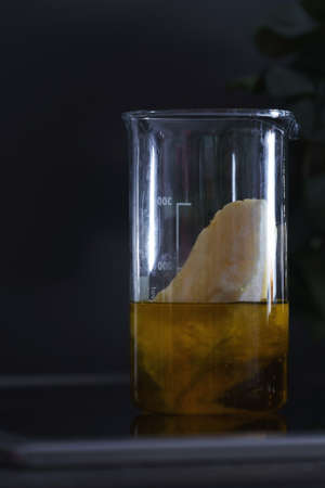 Solid butter and plant based oil mixed in glass flask on ceramic stove surfaceの写真素材