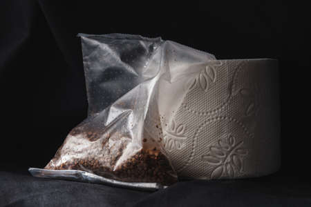 Toilet paper roll and a sack of buckwheat on rough black cloth backgroundの写真素材