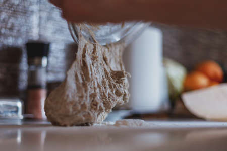 Close up of dough falling out of bowl onto table surface covered with flourの写真素材