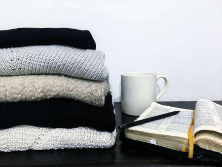 Autumn concept stack of sweaters, coffe cup and bookの写真素材