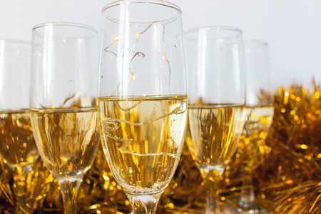 Glasses with champagne with gold tinsel on light gray backgroundの写真素材