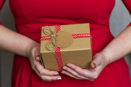 A gift box that holds a woman in a red dress. Festive concept.