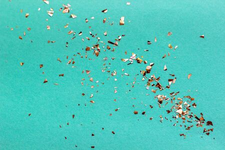 Golden sparkles on mint background. Festive concept. Flat lay.