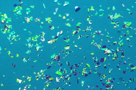 Multicolored holographic confetti on a blue background.の写真素材