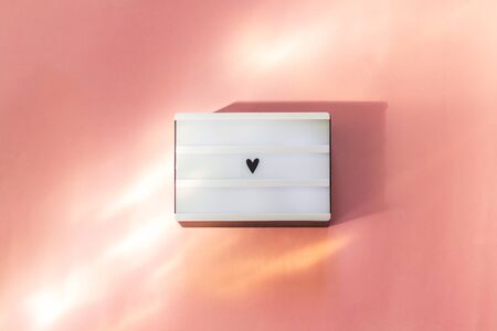 Light box with heart sign on pink background. Love St. Valentine's day backdrop or greeting card....