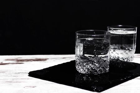 Water in the glasses on a white table against black background.の写真素材