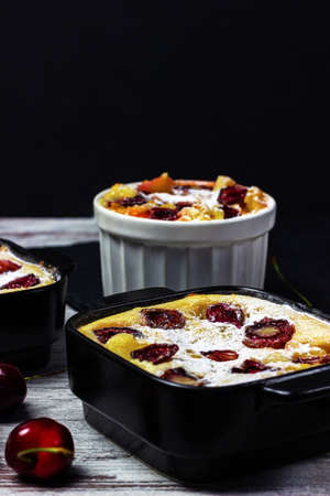 Clafoutis with cherry on dark background. Traditional french pie with seasonal fruits. Homemade...