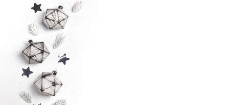 Festive border made of chrisrmas ornaments, white spruce branches, pine cones and silver star shaped...