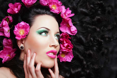 Young beautiful brunette  girl with pink flowers in her hair. pink flowerの写真素材