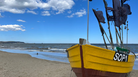Fishing boat on the beach with blue sky and white clouds.